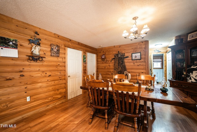 dining area with an inviting chandelier, hardwood / wood-style flooring, and a textured ceiling