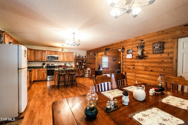 dining space featuring a textured ceiling, light hardwood / wood-style floors, and a chandelier