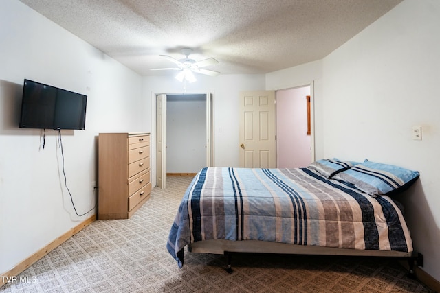 bedroom with ceiling fan, light colored carpet, and a textured ceiling