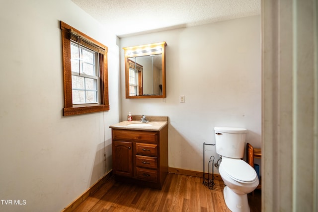 bathroom with vanity, toilet, hardwood / wood-style floors, and a textured ceiling