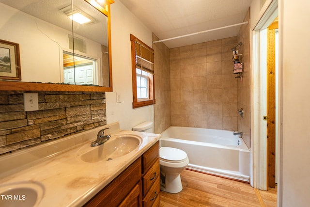 full bathroom featuring vanity, tiled shower / bath combo, toilet, and hardwood / wood-style flooring