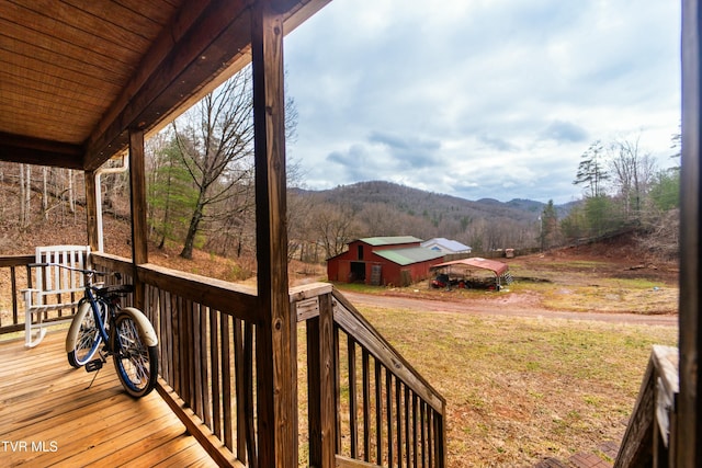 wooden terrace featuring an outbuilding, a mountain view, and a lawn