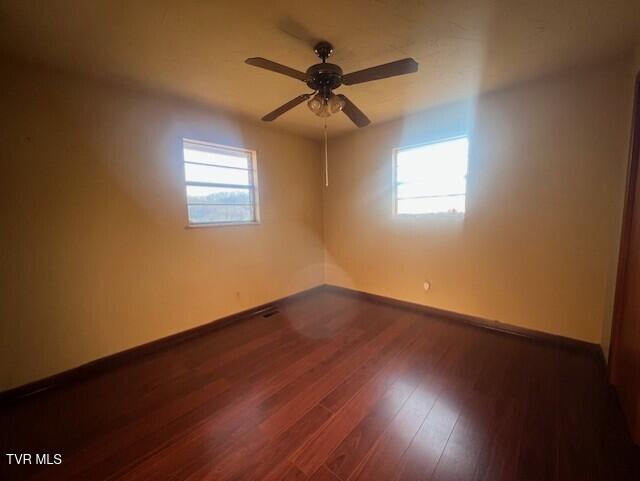 unfurnished room with ceiling fan, a healthy amount of sunlight, and dark hardwood / wood-style flooring