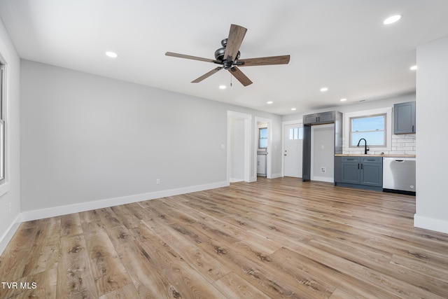 unfurnished living room with ceiling fan, sink, and light wood-type flooring