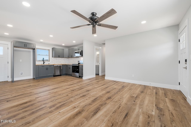 unfurnished living room featuring sink, light hardwood / wood-style flooring, and ceiling fan