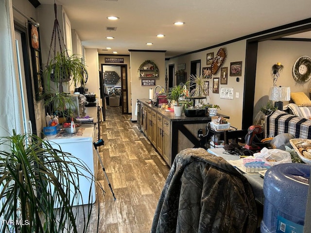 kitchen featuring sink, crown molding, light hardwood / wood-style flooring, a center island, and washer / dryer