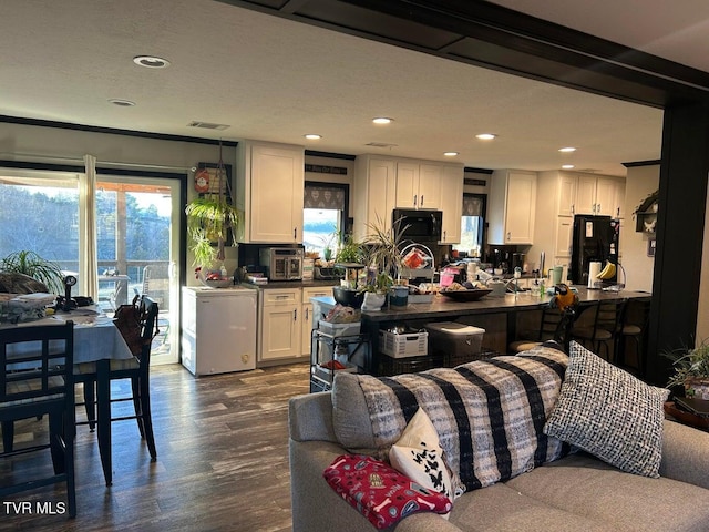 kitchen with dark wood-type flooring, white cabinets, and black appliances