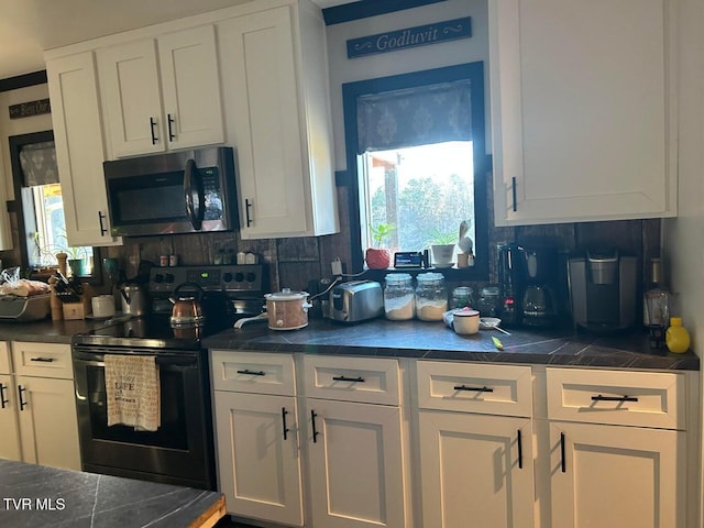 kitchen featuring white cabinetry, a wealth of natural light, backsplash, and black / electric stove