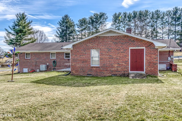 back of property with central AC and a lawn