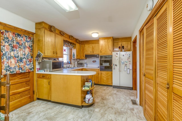 kitchen featuring sink, black oven, kitchen peninsula, and white refrigerator