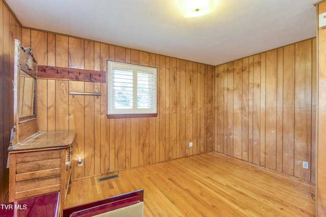 spare room featuring wooden walls and light hardwood / wood-style flooring