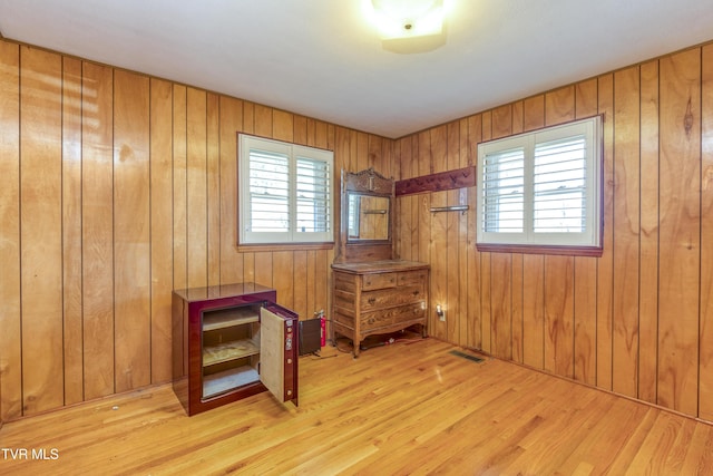 misc room featuring light hardwood / wood-style flooring, wood walls, and plenty of natural light