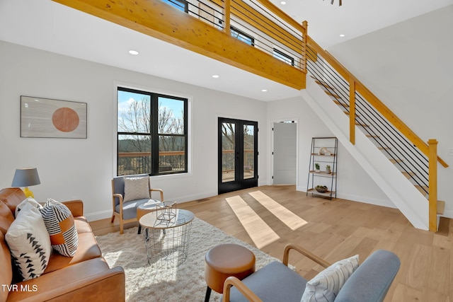 living room with a high ceiling, light hardwood / wood-style floors, and french doors