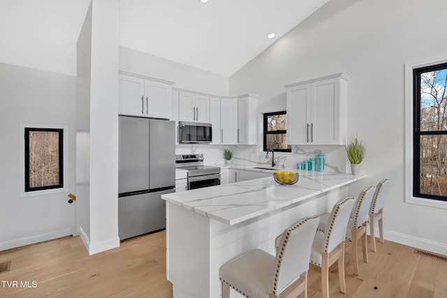 kitchen with stainless steel appliances, white cabinetry, sink, and kitchen peninsula