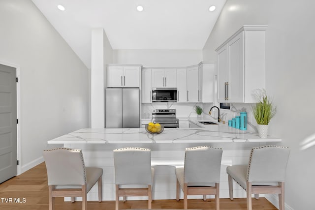 kitchen with white cabinetry, sink, light stone countertops, and appliances with stainless steel finishes