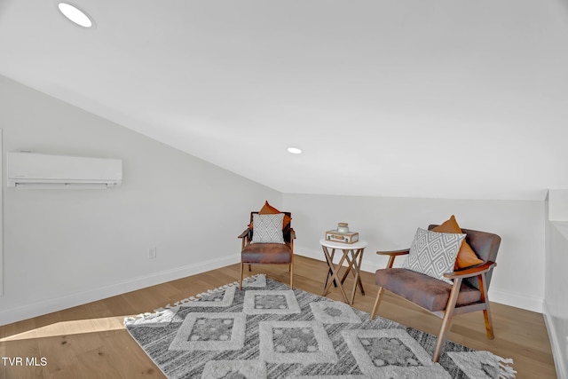 living area featuring lofted ceiling, a wall mounted air conditioner, and light hardwood / wood-style flooring