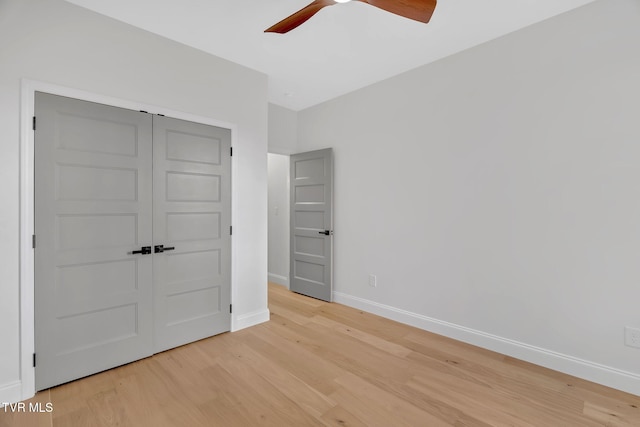 unfurnished bedroom featuring ceiling fan, a closet, and light wood-type flooring