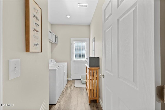 clothes washing area featuring washing machine and clothes dryer and wood-type flooring