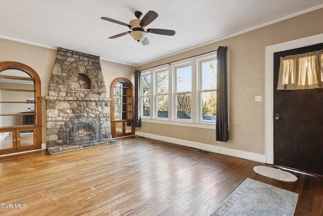 unfurnished living room featuring ornamental molding, a fireplace, wood finished floors, and baseboards