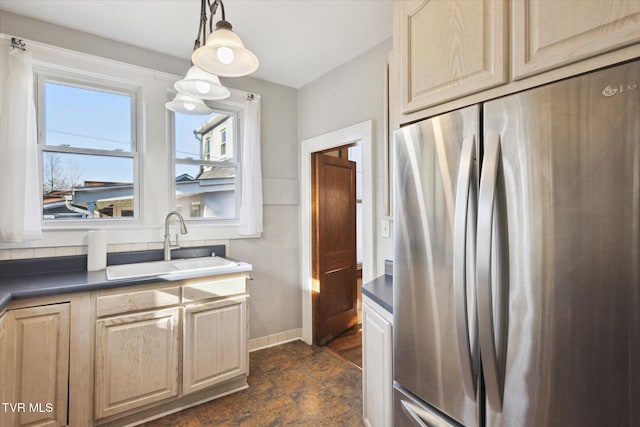 kitchen with baseboards, dark countertops, decorative light fixtures, freestanding refrigerator, and a sink