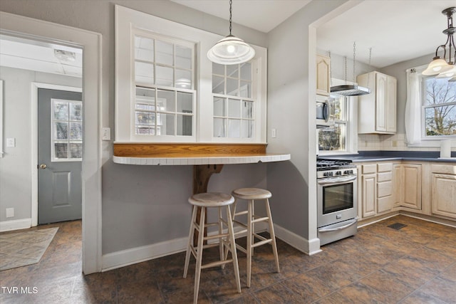 kitchen with tasteful backsplash, stainless steel range with gas cooktop, pendant lighting, and baseboards