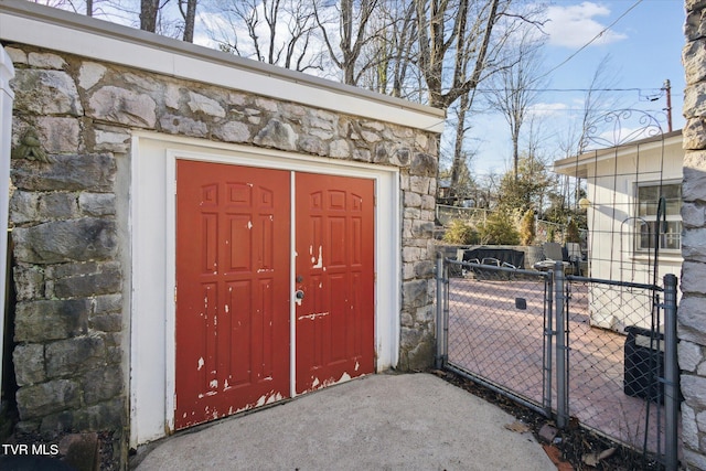 doorway to property featuring stone siding, fence, and a gate