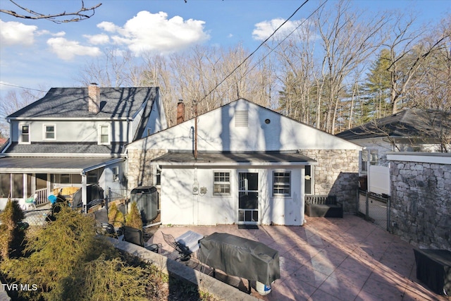 rear view of house featuring a chimney, fence, a gate, and stucco siding