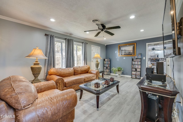 living room featuring ceiling fan, ornamental molding, a textured ceiling, and light wood-type flooring