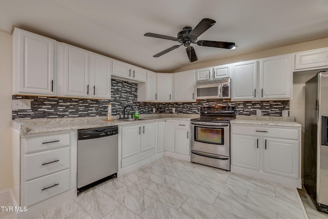 kitchen with sink, white cabinetry, light stone counters, stainless steel appliances, and decorative backsplash