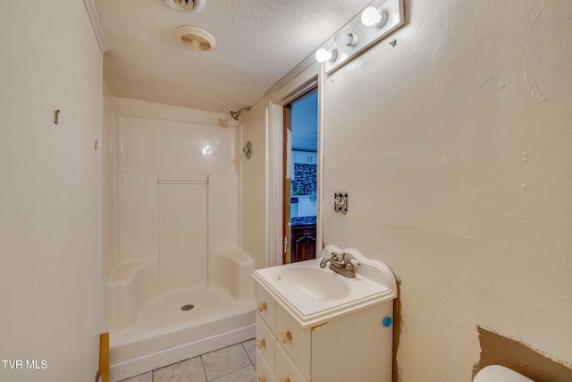 bathroom featuring vanity, tile patterned flooring, a textured ceiling, and a shower