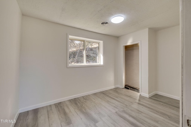 empty room featuring light hardwood / wood-style flooring and a textured ceiling