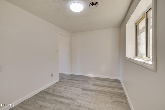 spare room with a textured ceiling and light hardwood / wood-style floors