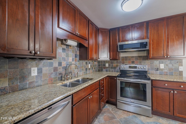 kitchen featuring sink, decorative backsplash, light stone countertops, and appliances with stainless steel finishes