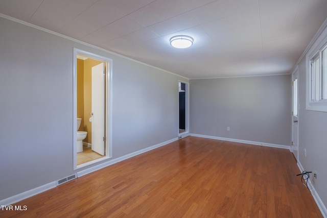 empty room with crown molding and light hardwood / wood-style flooring