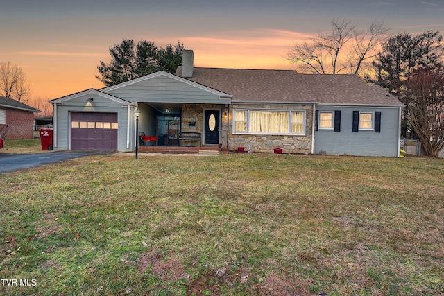 ranch-style house with a yard, aphalt driveway, a chimney, and an attached garage