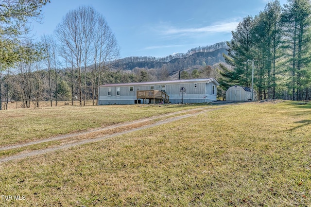 view of front of house featuring a deck with mountain view, a shed, and a front yard