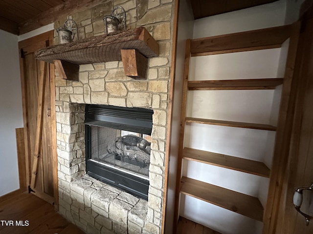 room details with a stone fireplace and hardwood / wood-style flooring