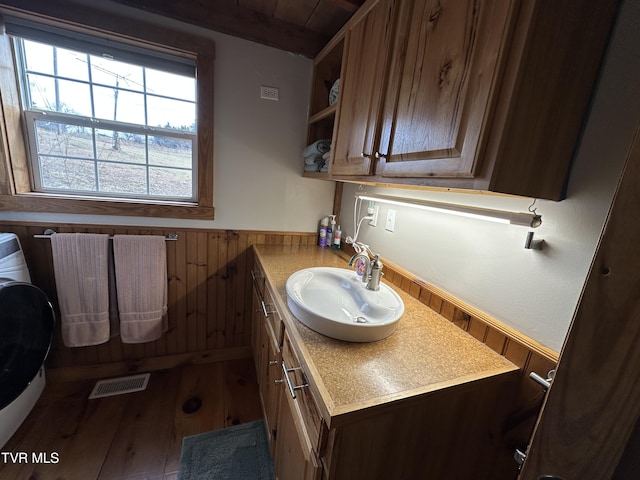 bathroom featuring sink, hardwood / wood-style flooring, and wood walls