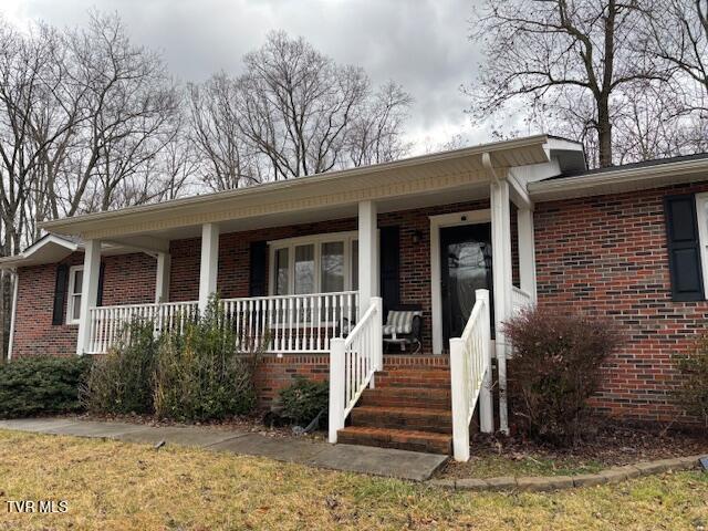 view of front of home featuring covered porch and brick siding