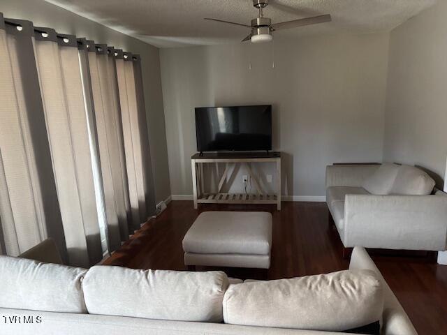 living room with wood finished floors, a ceiling fan, and baseboards