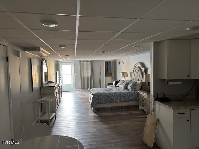 bedroom featuring dark wood-type flooring and a drop ceiling