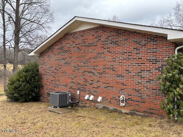 view of side of property with central AC and brick siding