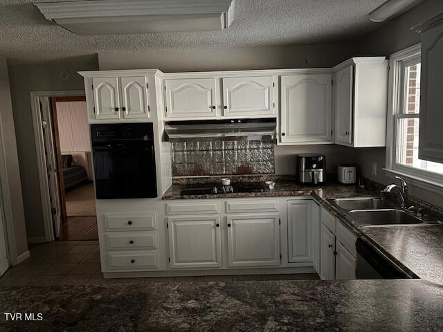 kitchen with a healthy amount of sunlight, a sink, under cabinet range hood, and black appliances