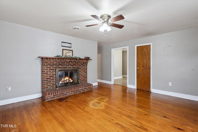 unfurnished living room featuring a brick fireplace, hardwood / wood-style flooring, and ceiling fan