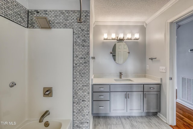 bathroom featuring vanity, wood-type flooring, ornamental molding, a textured ceiling, and shower / bathtub combination