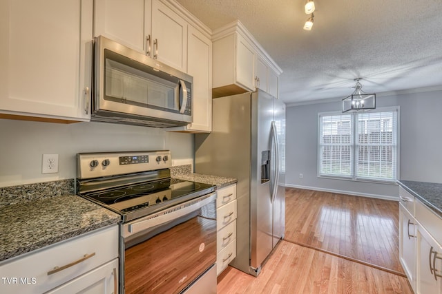 kitchen with light hardwood / wood-style flooring, appliances with stainless steel finishes, white cabinetry, ornamental molding, and a textured ceiling