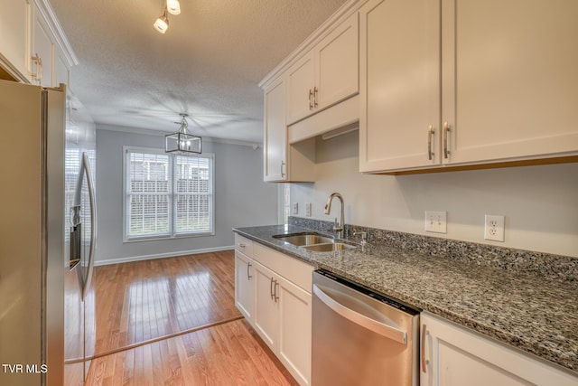 kitchen featuring appliances with stainless steel finishes, white cabinetry, sink, dark stone counters, and light hardwood / wood-style floors