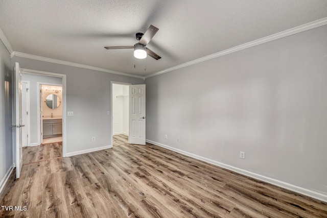 unfurnished bedroom with light hardwood / wood-style flooring, ceiling fan, ensuite bathroom, ornamental molding, and a textured ceiling