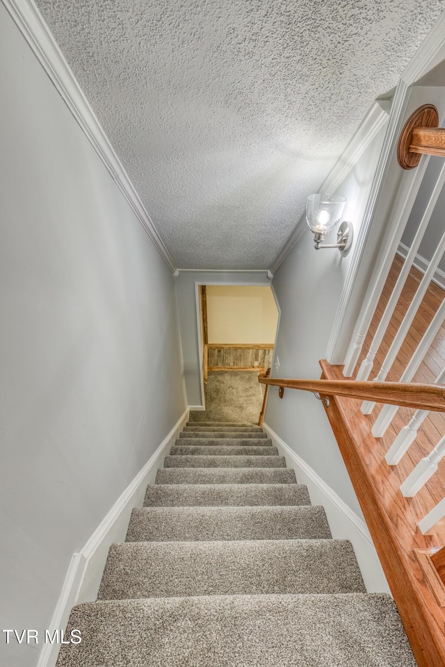 staircase featuring ornamental molding and a textured ceiling