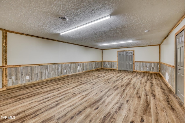 unfurnished room featuring ornamental molding, a textured ceiling, and light wood-type flooring